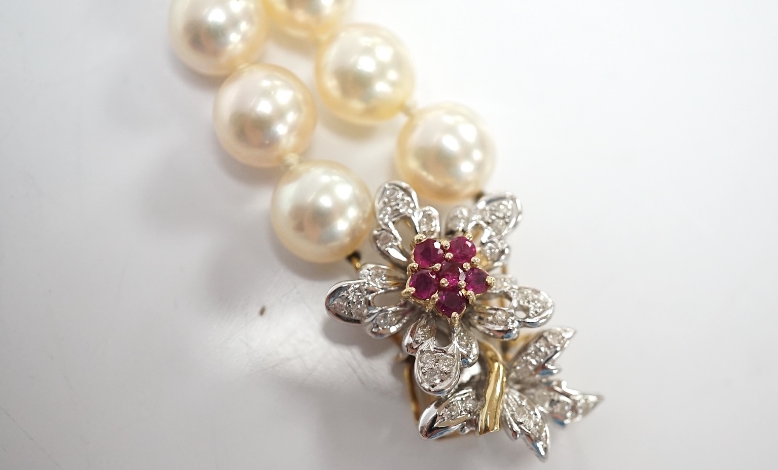 A double strand cultured pearl bracelet, with a ruby and diamond cluster set 14k clasp, 17.3cm. Condition - good